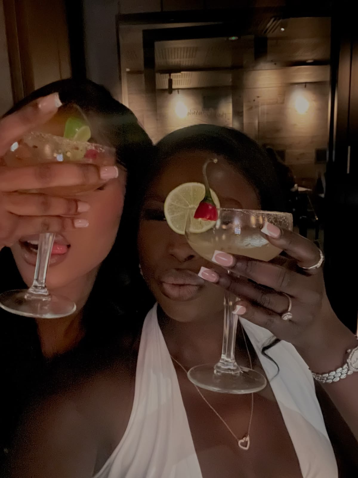 Two women smiling with cocktails at a dinner table