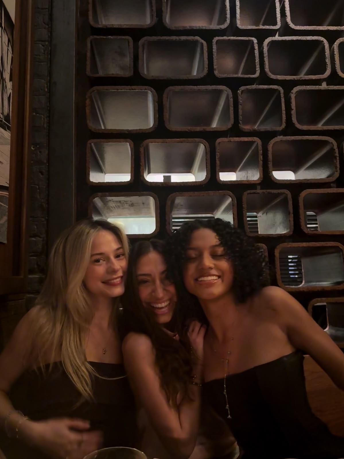 Three women laughing together at a Dinner with the Girls table